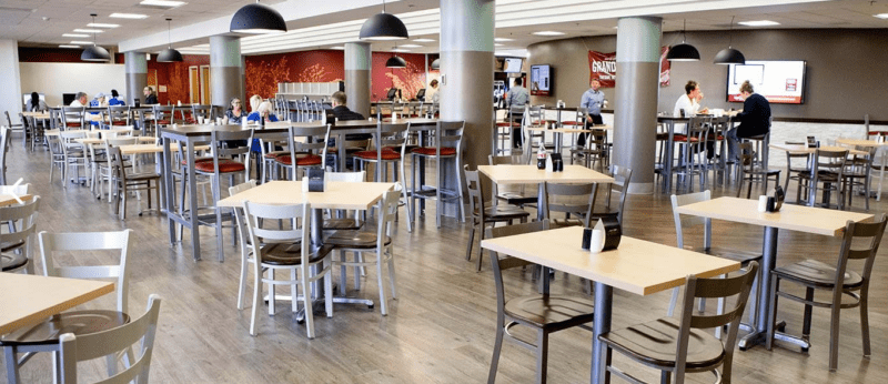 Morrison Healthcare dining area with people seated at tables and chairs under hanging light fixtures