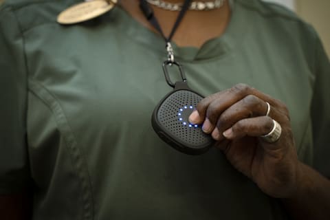 Person holding medical alert device pendant, close-up of hands